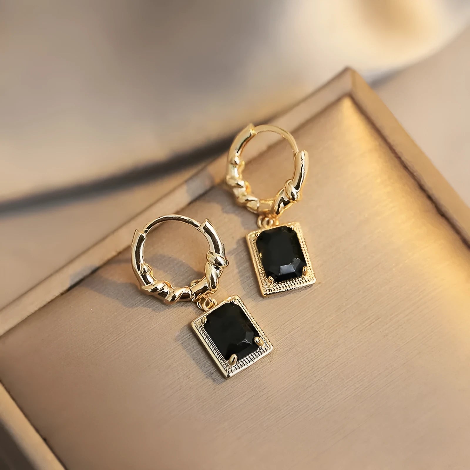 Close-up of black geometric cubic zirconia earrings with a quadrilateral design and butterfly clutch backs.