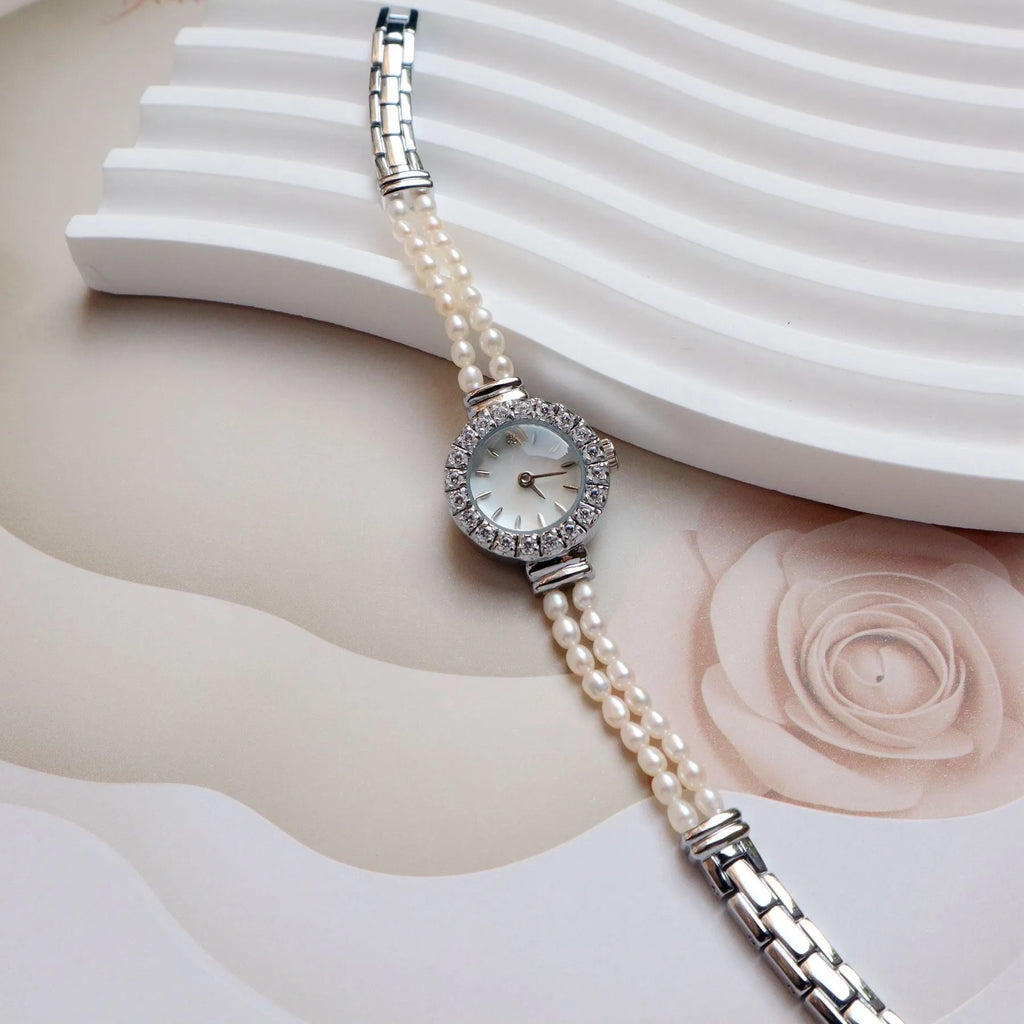 Women's light gold bracelet watch with freshwater pearls, showing 18mm round dial and stainless steel strap.