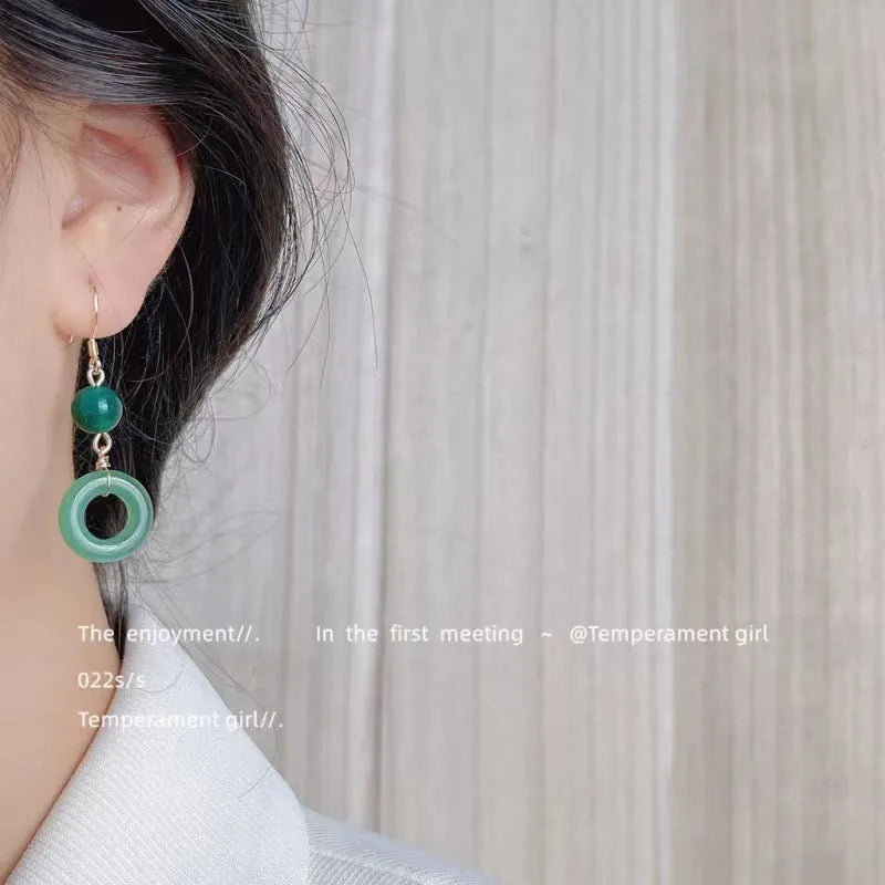 A pair of geometric peace buckle earrings with a green jade design and gold plating.