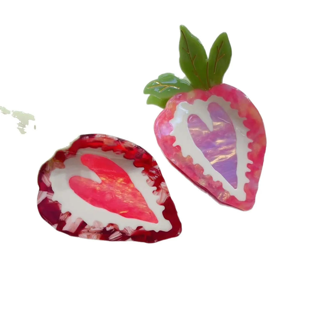 Close-up of a handmade strawberry decorative hair clip on a pink background.