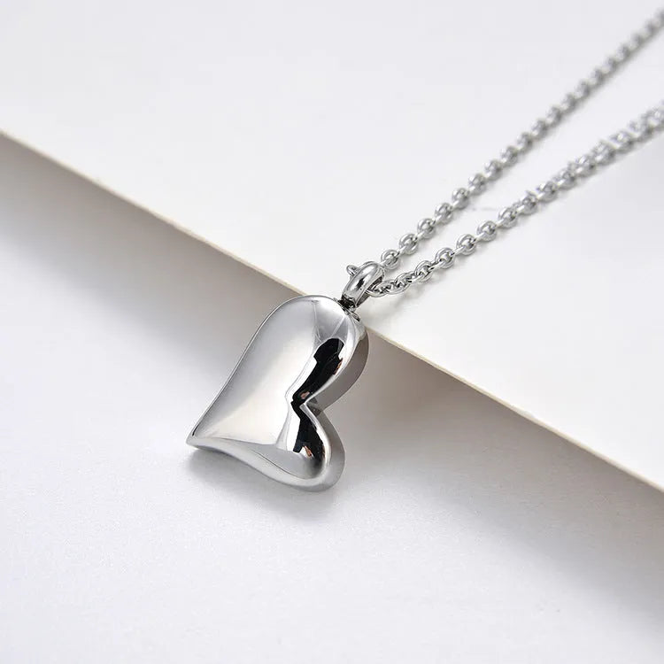 Silver curved peach heart pendant necklace with adjustable chain on grey background