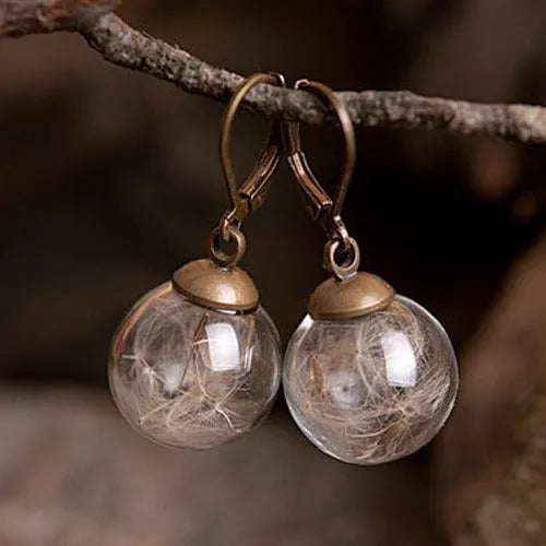 Close-up of a woman's ear wearing 16mm transparent glass ball dandelion seed earrings on a silver French hook.