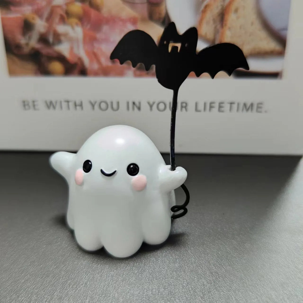 Small white resin statue of a ghost walking a bat on a Halloween lead