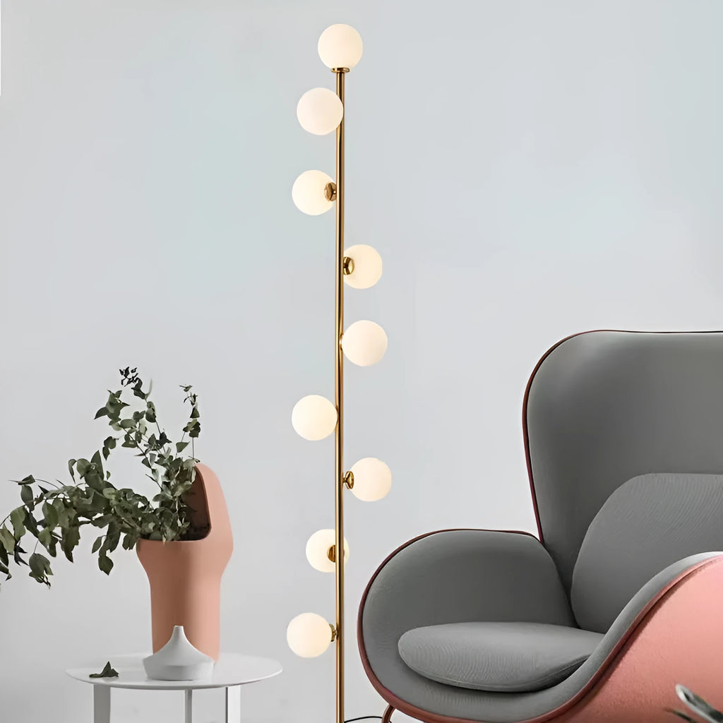 Tall modern floor lamp with slender iron frame, glass shade, and solid circular base in a minimalist living room setting.