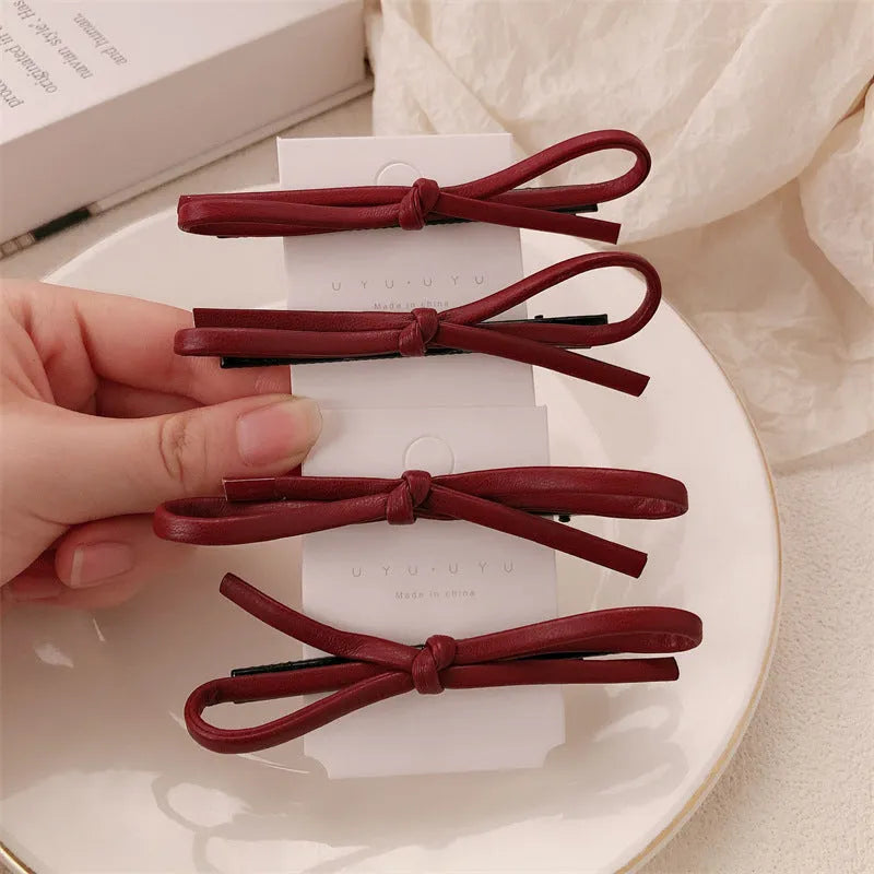 Wine red genuine leather bow attached to a metal hair clip, shown on a background.