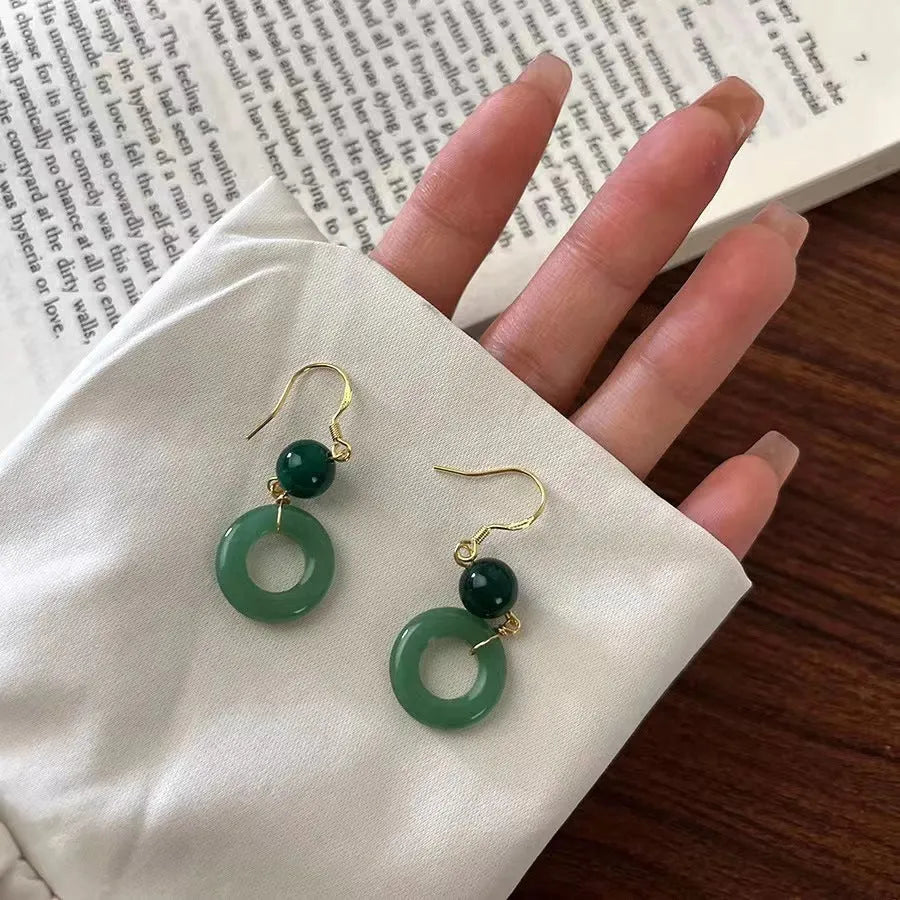 A pair of geometric peace buckle earrings with a green jade design and gold plating.