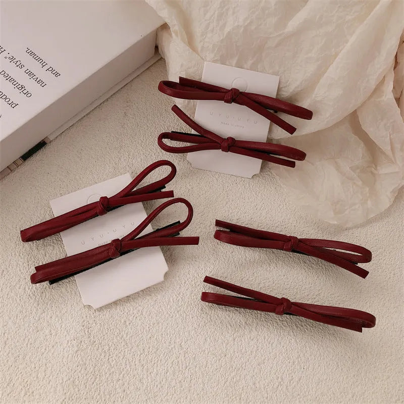 Wine red genuine leather bow attached to a metal hair clip, shown on a background.