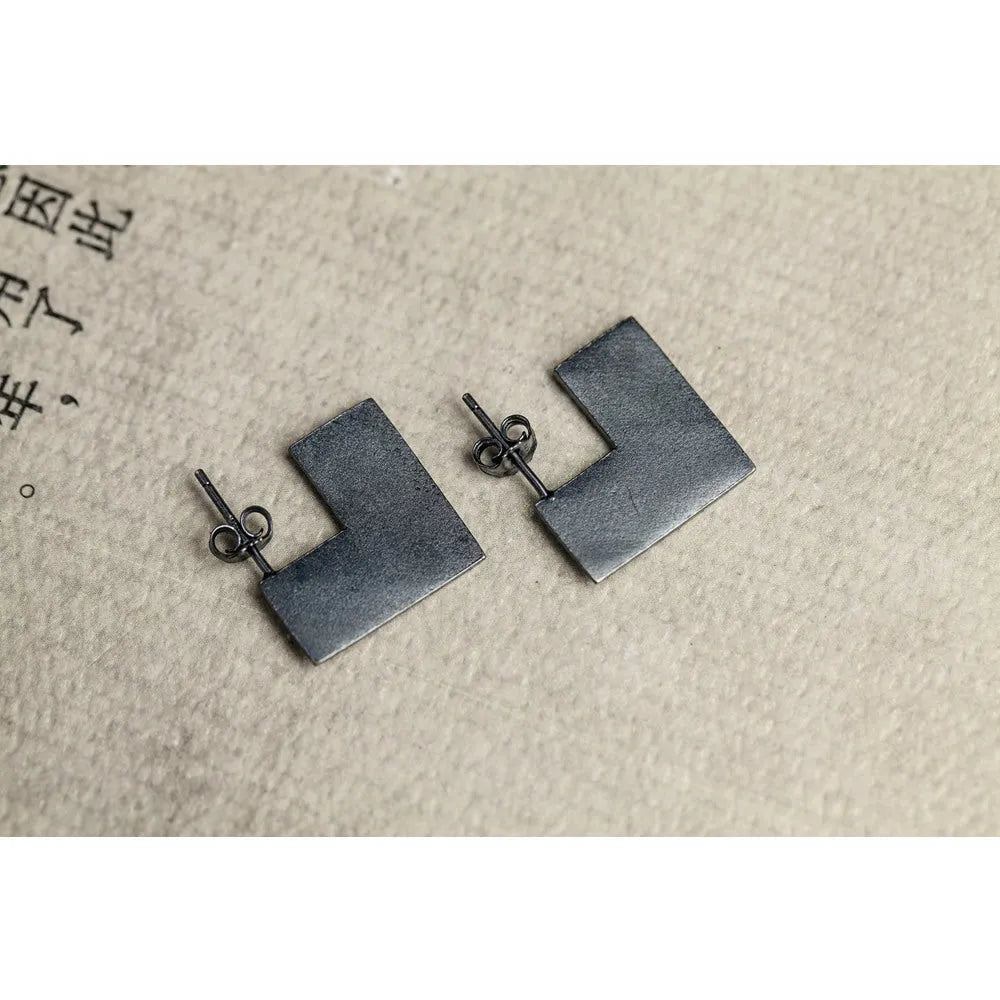 Oxidised black sterling silver square geometric earrings on a white background.