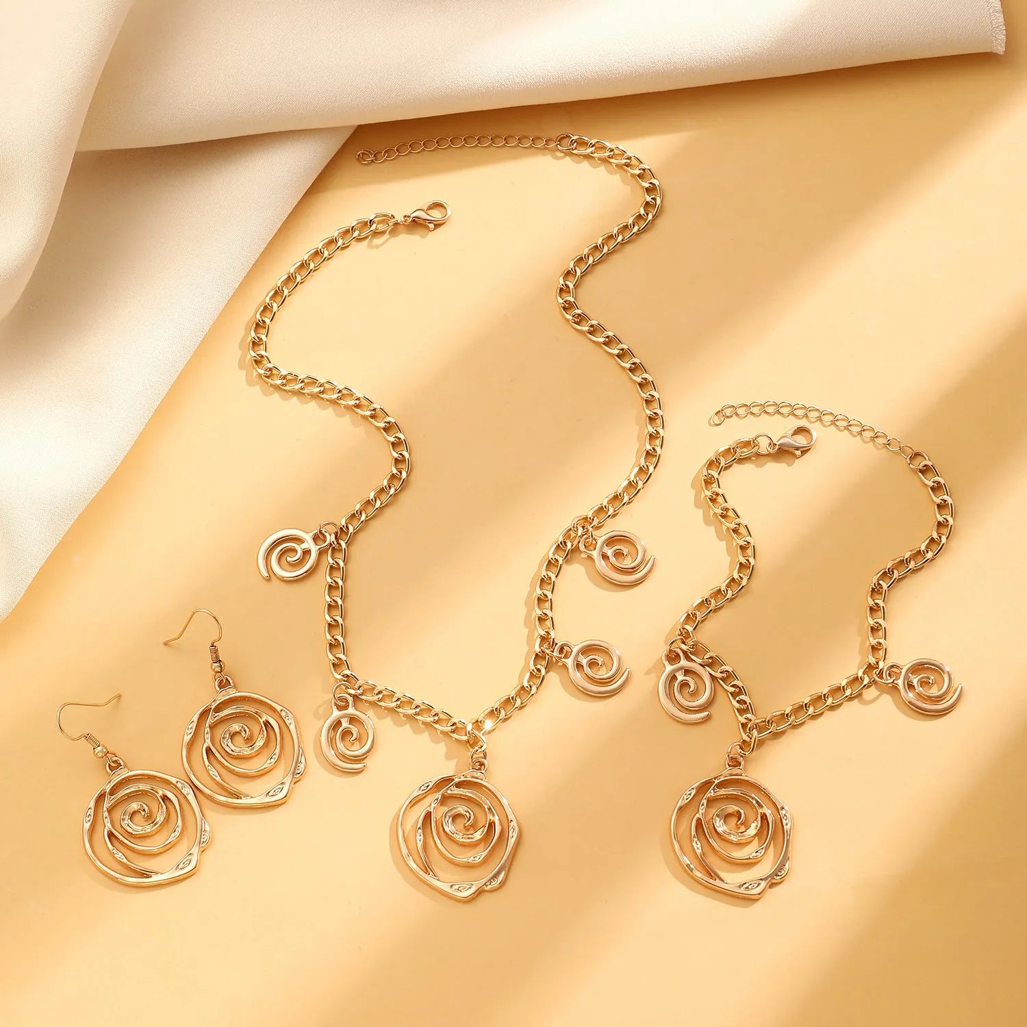 Spiral donut jewellery set showing necklace, bracelet and ear hooks with geometric circle designs in gold finish