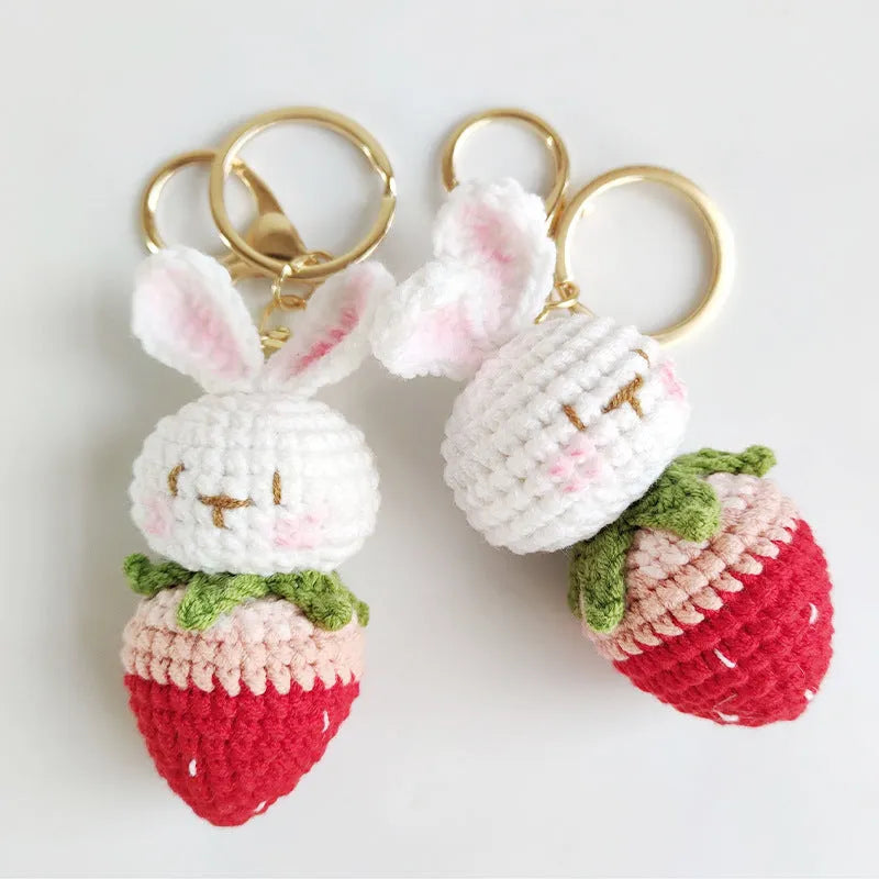 White hand-woven wire pendant with a cartoon rabbit and strawberry design, shown with a metal key.