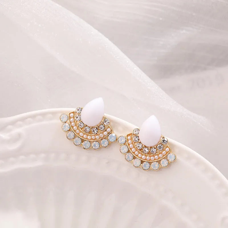 A pair of silver retro fan-shaped stud earrings with rhinestone details on a geometric design.