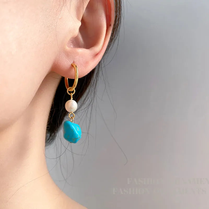 A pair of geometric copper clip-on earrings featuring irregular blue-green turquoise stones and white cultured pearls.