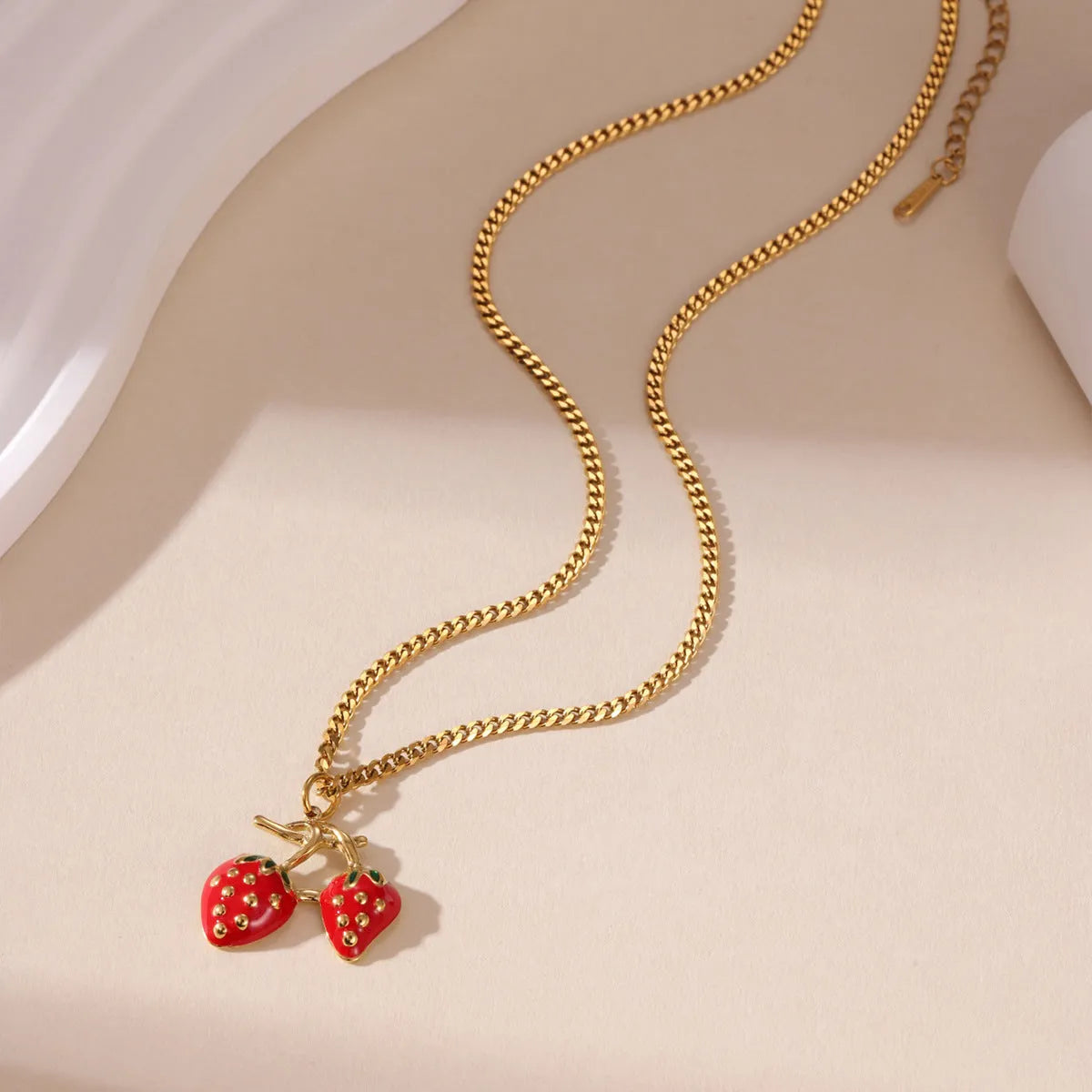 A stainless steel necklace with a strawberry fruit pendant in either red or white gradient colour.