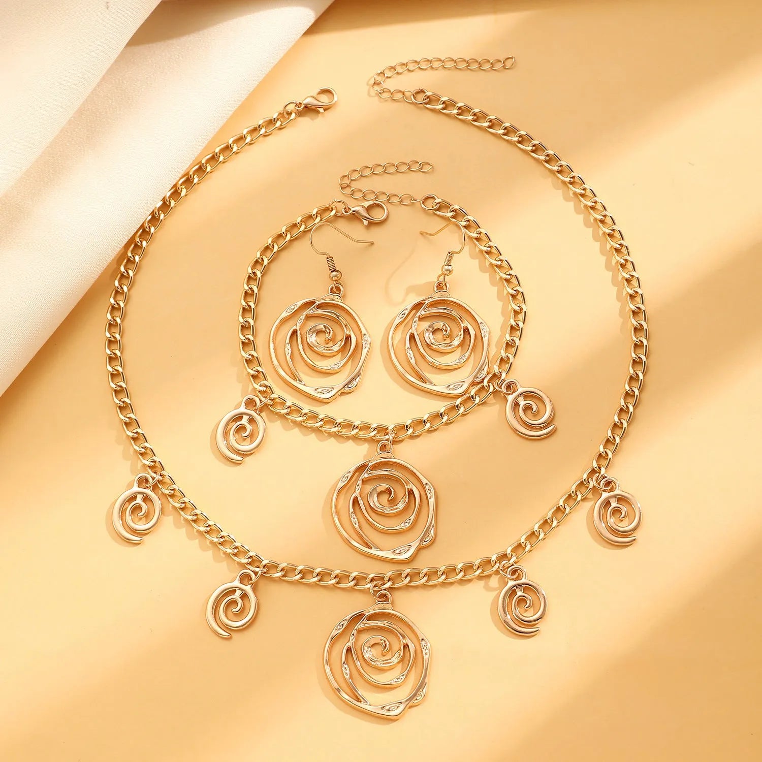 Spiral donut jewellery set showing necklace, bracelet and ear hooks with geometric circle designs in gold finish