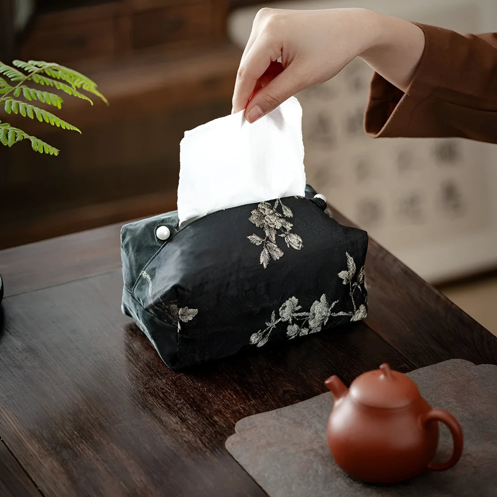 White embroidered plum blossom tissue box cover with fabric texture, shown next to a standard tissue carton for scale.