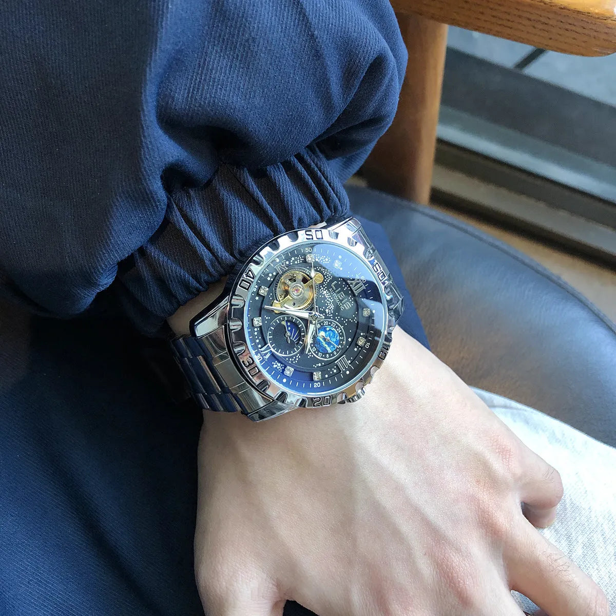 Men's silver automatic watch with black starry luminous dial on a leather strap.