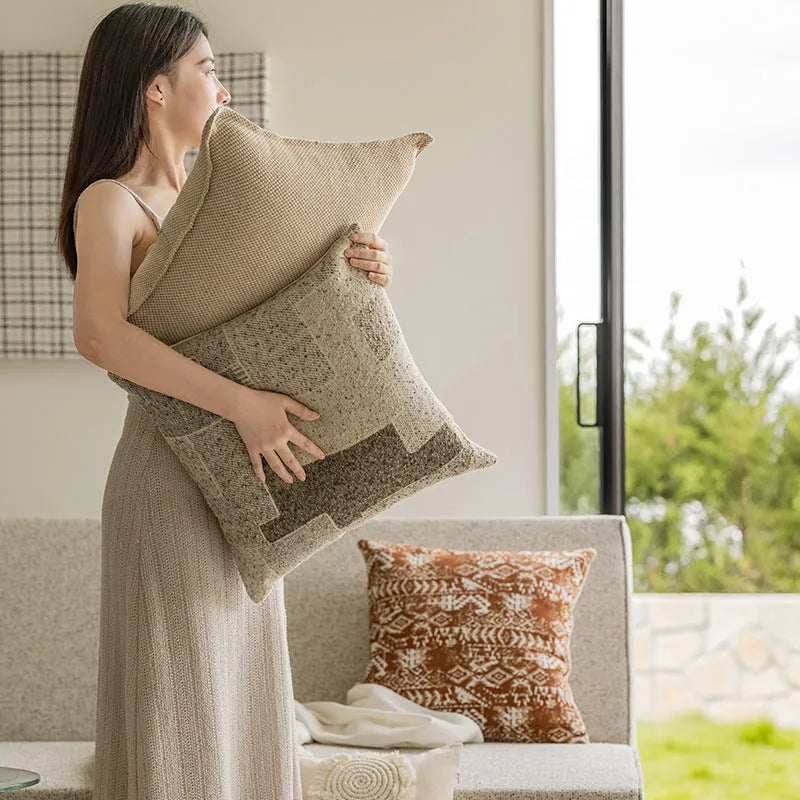 A square pp cotton pillow cushion with a solid red-brown abstract print cover on a sofa.