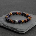 Handmade elastic bracelet with natural tiger-eye stones in geometric cut, yellow purple red colour variations