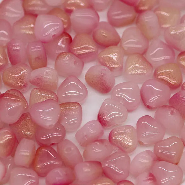 Twenty transparent love heart shaped spacer beads in assorted colours on a white background.