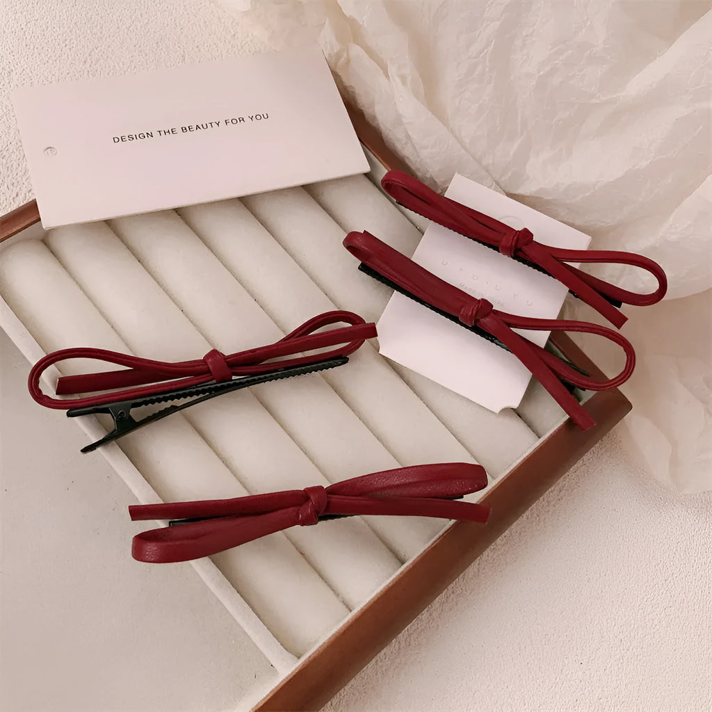 Wine red genuine leather bow attached to a metal hair clip, shown on a background.