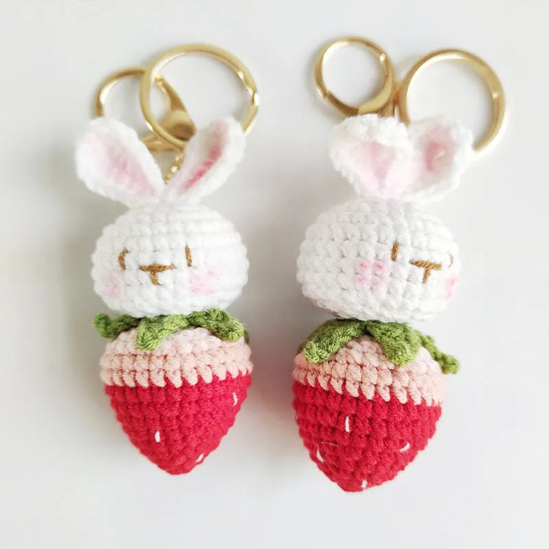White hand-woven wire pendant with a cartoon rabbit and strawberry design, shown with a metal key.