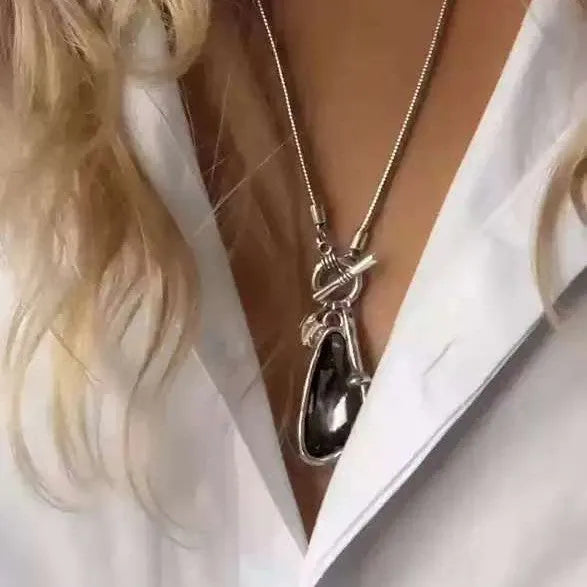 Geometric alloy pendant with plaid pattern on a long snake bones chain necklace.