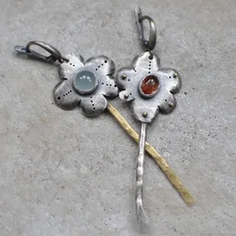 A pair of long, geometric flower-shaped drop earrings with an asymmetric two-tone metallic finish.