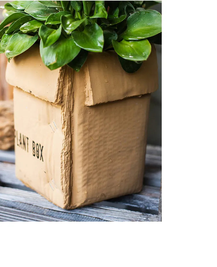 Cement brown paper box design flower pot with bottom drainage holes on a table.