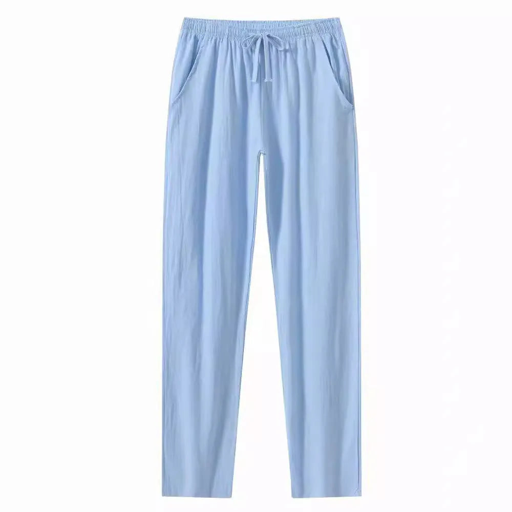 Men's loose-fitting cotton beach trousers in a solid colour, shown in a casual setting.