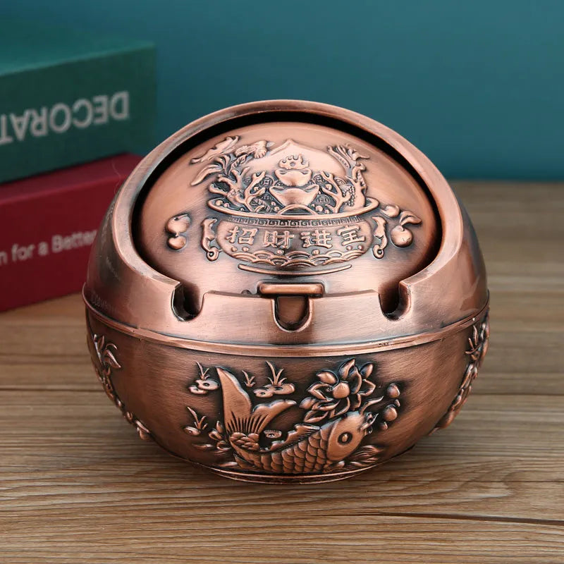 Alloy decorative ashtray in bronze with ornate peacock motif and cigarette extinguishing slot.