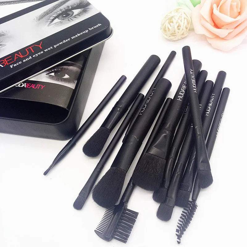 12 makeup brushes with corrugated silk nylon bristles and wooden handles in a black tin box on a flat surface.