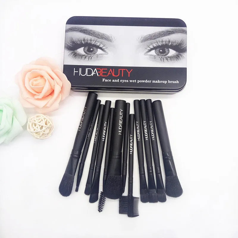 12 makeup brushes with corrugated silk nylon bristles and wooden handles in a black tin box on a flat surface.