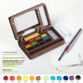 Mini walnut wood watercolour paint box open to show a set of professional paint pigments.