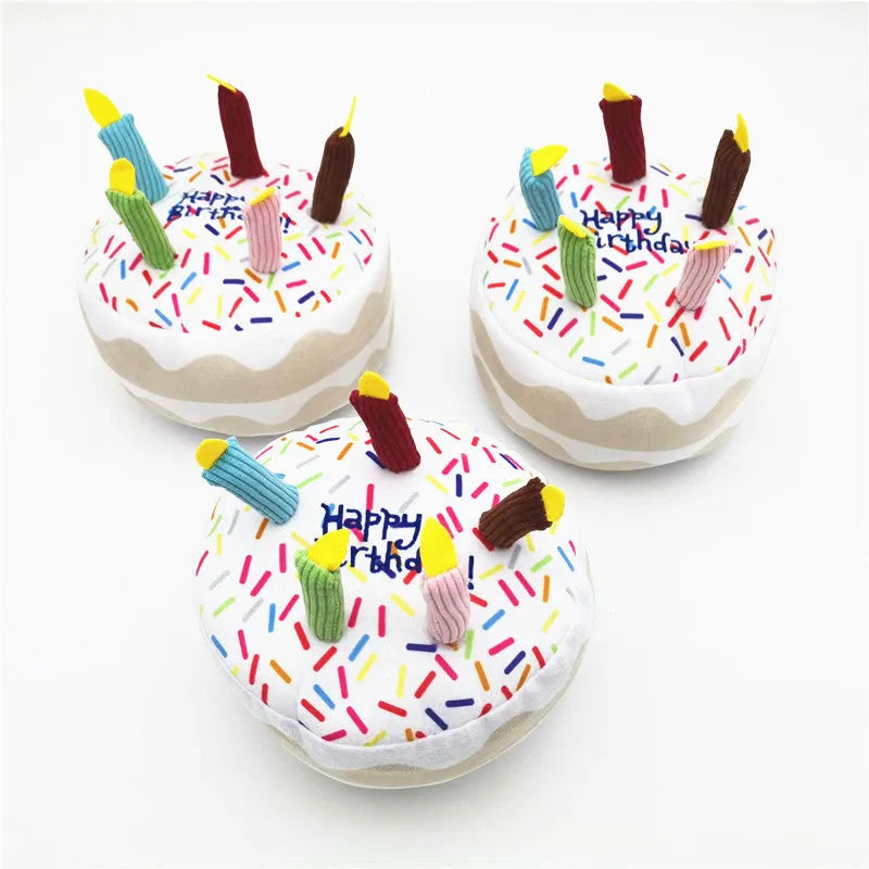 Four soft plush dog birthday toys: large cake, small cake, gift box, and bones on neutral background
