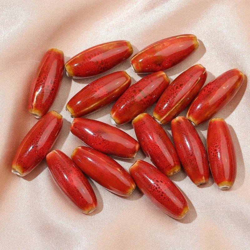 Assortment of ceramic bullet beads in pink, yellow, blue, red, coffee, green, orange, and mixed flower glaze colours.