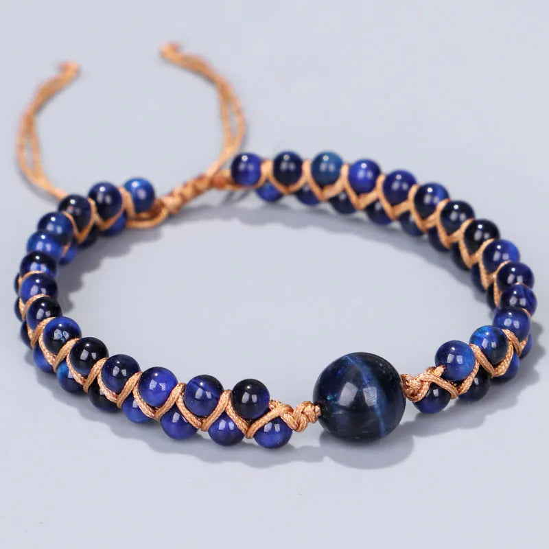 Close-up of a handmade woven bracelet featuring blue tigereye beads in a geometric pattern on a wrist.