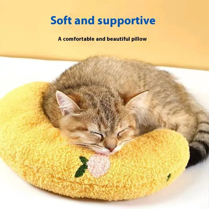 Blue U-shaped cloth pillow for cats on a wooden floor, showing its head-cradling design.