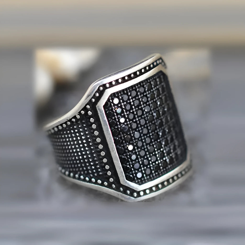 Black alloy ring with copper metal inlay and sparkling zircon stone accents on a finger.