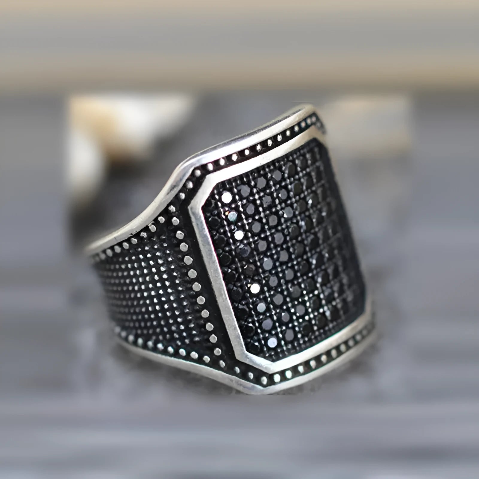 Black alloy ring with copper metal inlay and sparkling zircon stone accents on a finger.