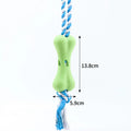 Green porous bone-shaped dog toy with rope knots for treat dispensing and dental chewing