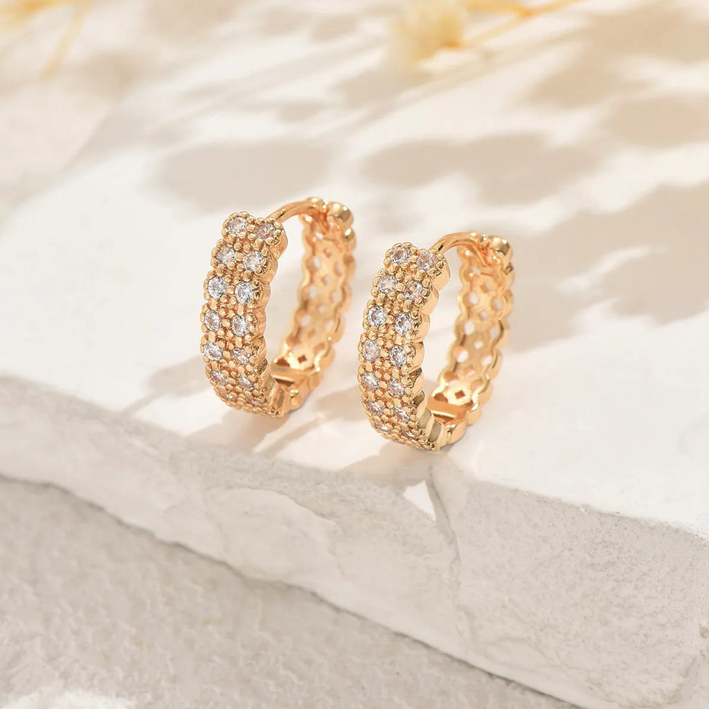 A pair of copper geometric ear studs featuring a round ring with a central dot, on a grey background.