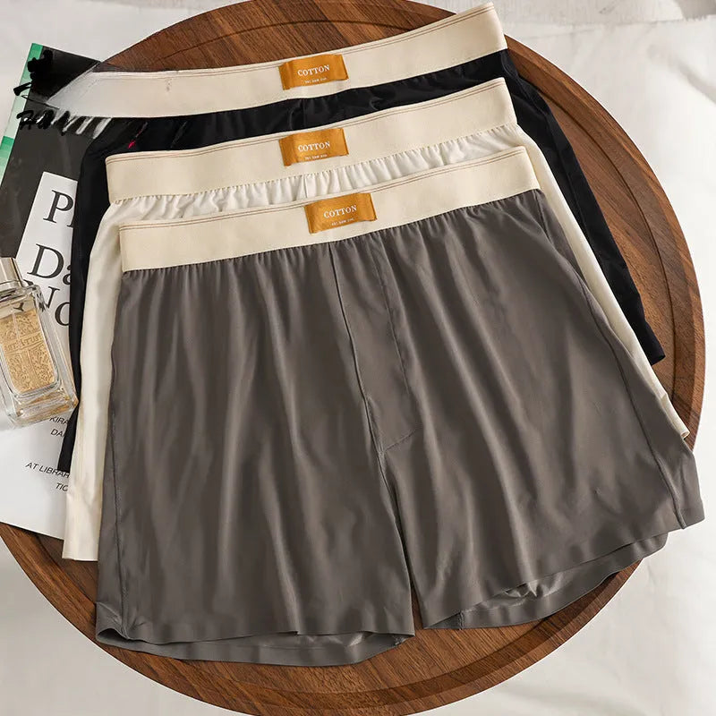 Men's solid colour loose ice silk underwear in beige, black, and grey shades laid flat