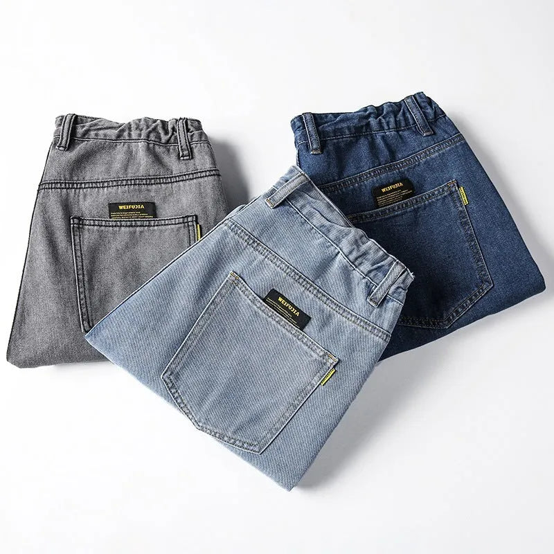 Men's dark blue loose straight-leg cotton jeans on a hanger, showing the simple style and mid-waist fit.