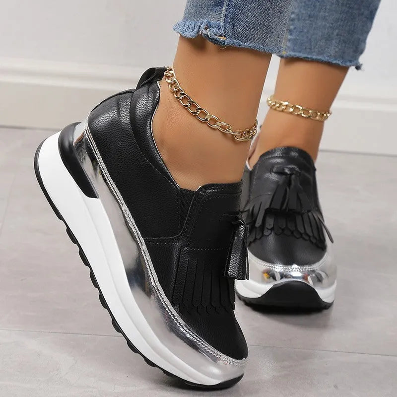Black women's platform shoes with a tassel on the front and a thick muffin wedge heel.