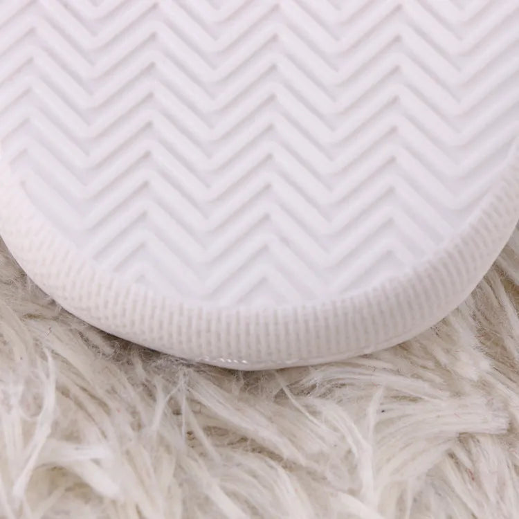 White adult fluffy slippers with cartoon pattern, rubber sole, and plush upper.
