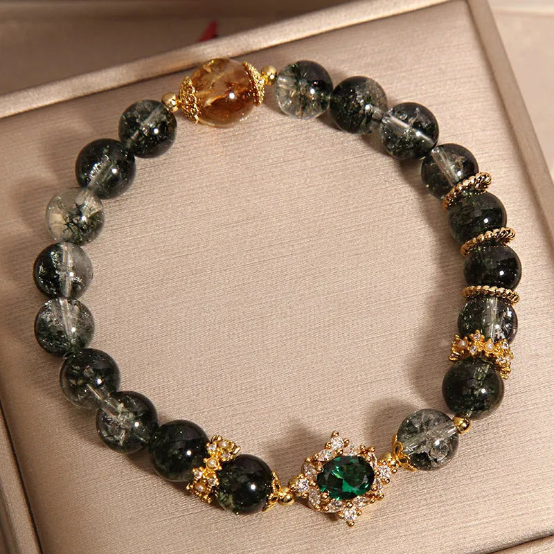 Gold electroplated women's bracelet with a green phantom quartz stone, ruby accents, rhinestones, and pearls.
