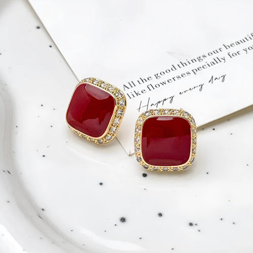 A pair of red geometric square alloy earrings with an inlaid plate design, showing front view.