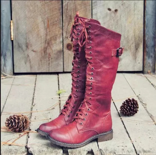 Black chunky heel high leg boots with a round toe and low heel on a plain background.
