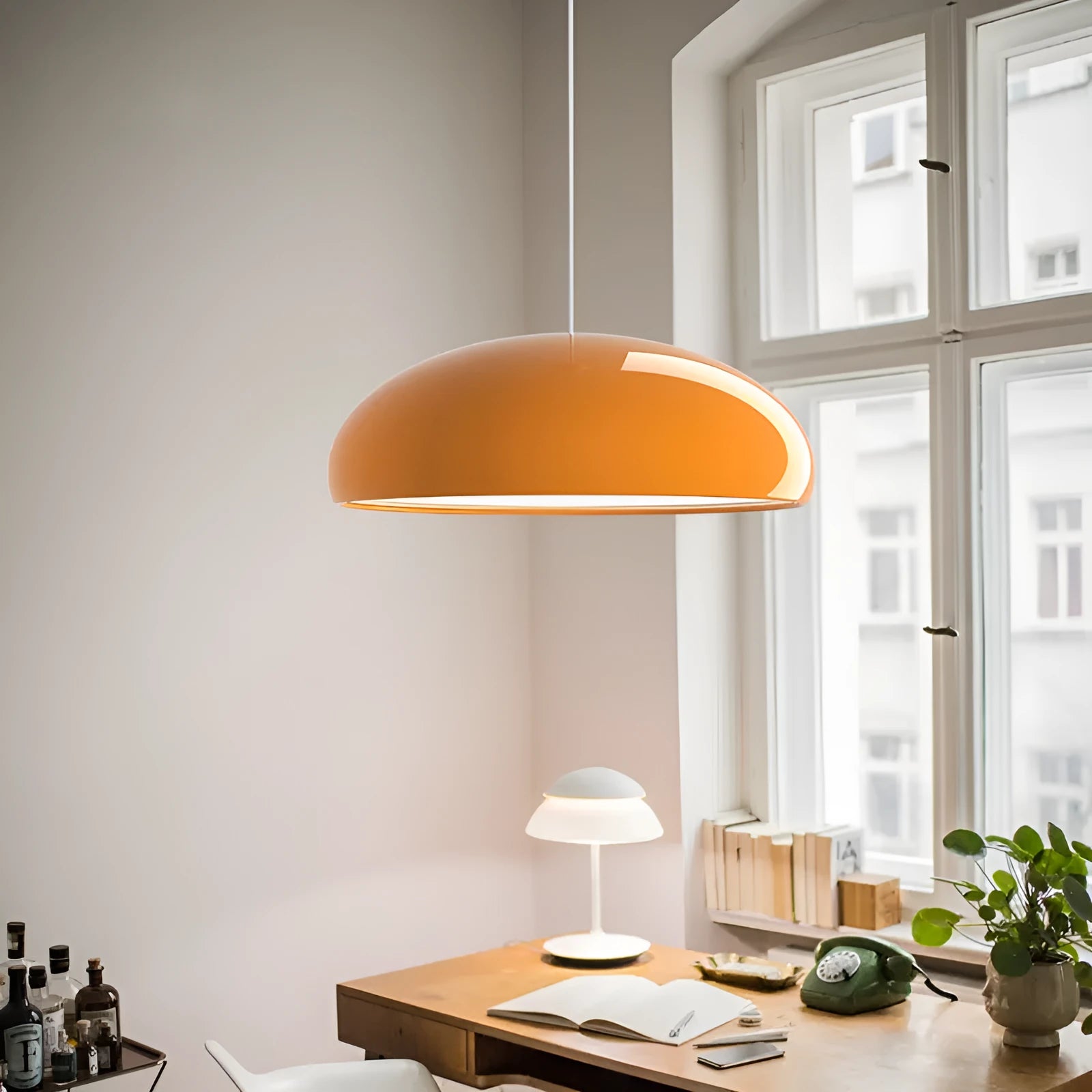 Danish-style iron pendant lamp with adjustable cord above a restaurant table.