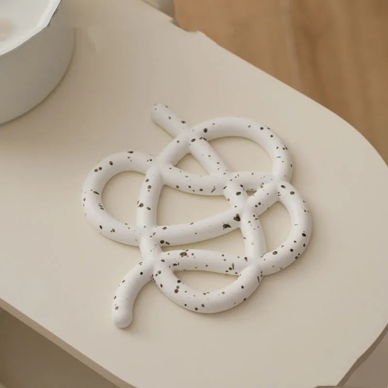 Ceramic heat proof mat in splash ink colour with bend and hook on wooden table